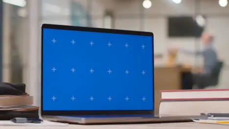 Blue Screen Laptop On Desk In Busy Modern Office 2