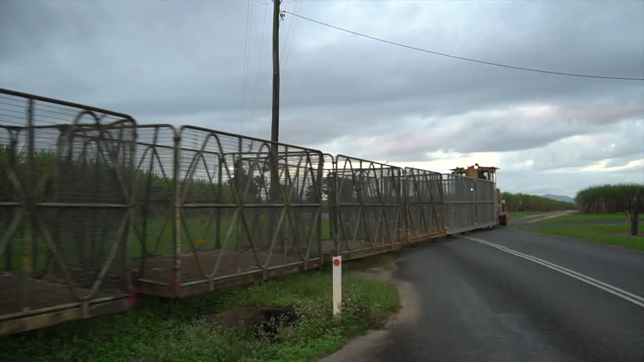 Empty yellow sugar cane train driving over road crossing