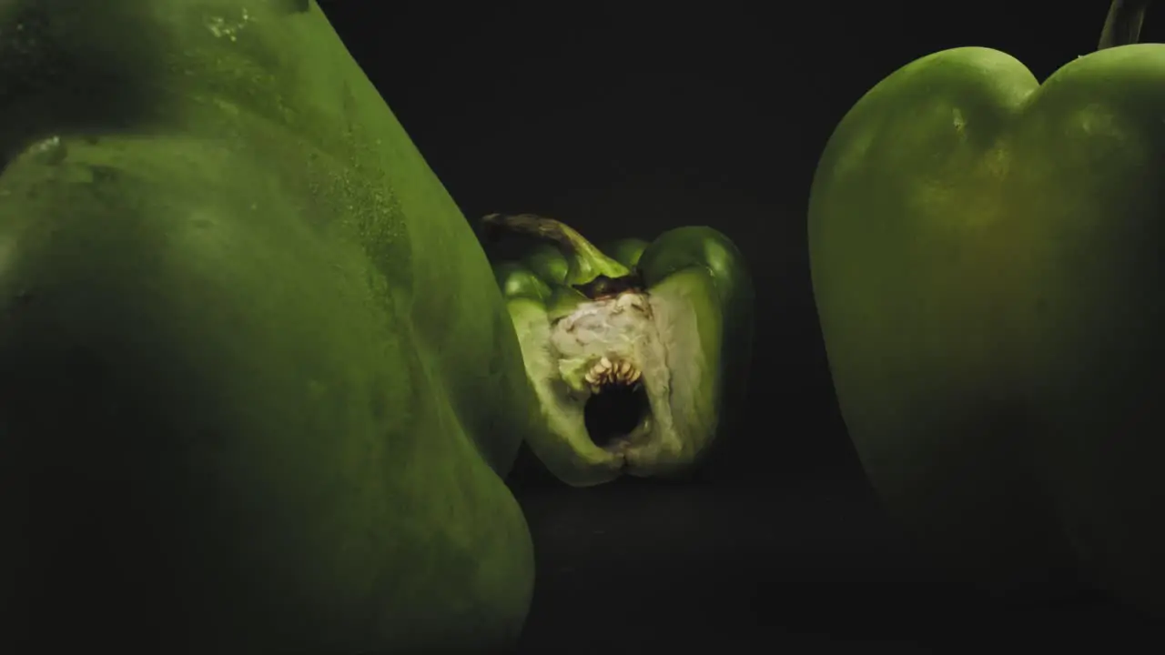 Three fresh green bell peppers one sliced open