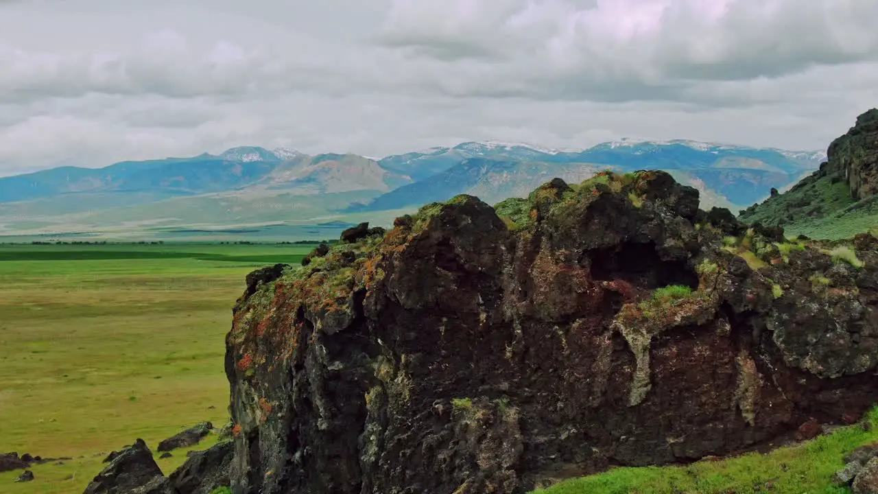 Black Rocky Green Hills with Bird Flyby Aerial Drone Footage Fast on Cloudy Day revealing majestic mountains in the distance near Interstate 15 in Central Utah USA