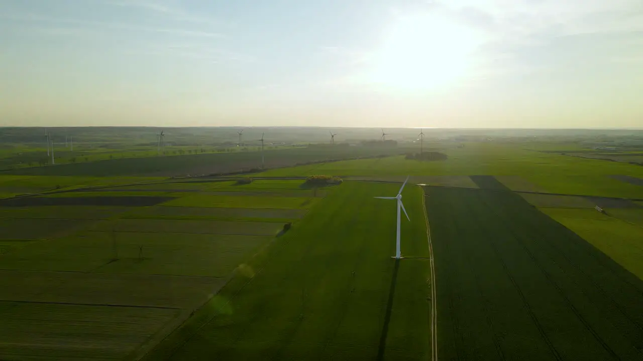 Wind farm over green fields on sunset viewed from a high point Aerial view of wind turbines slowly rotating under the wind in Puck Pomorskie Poland aerial drone