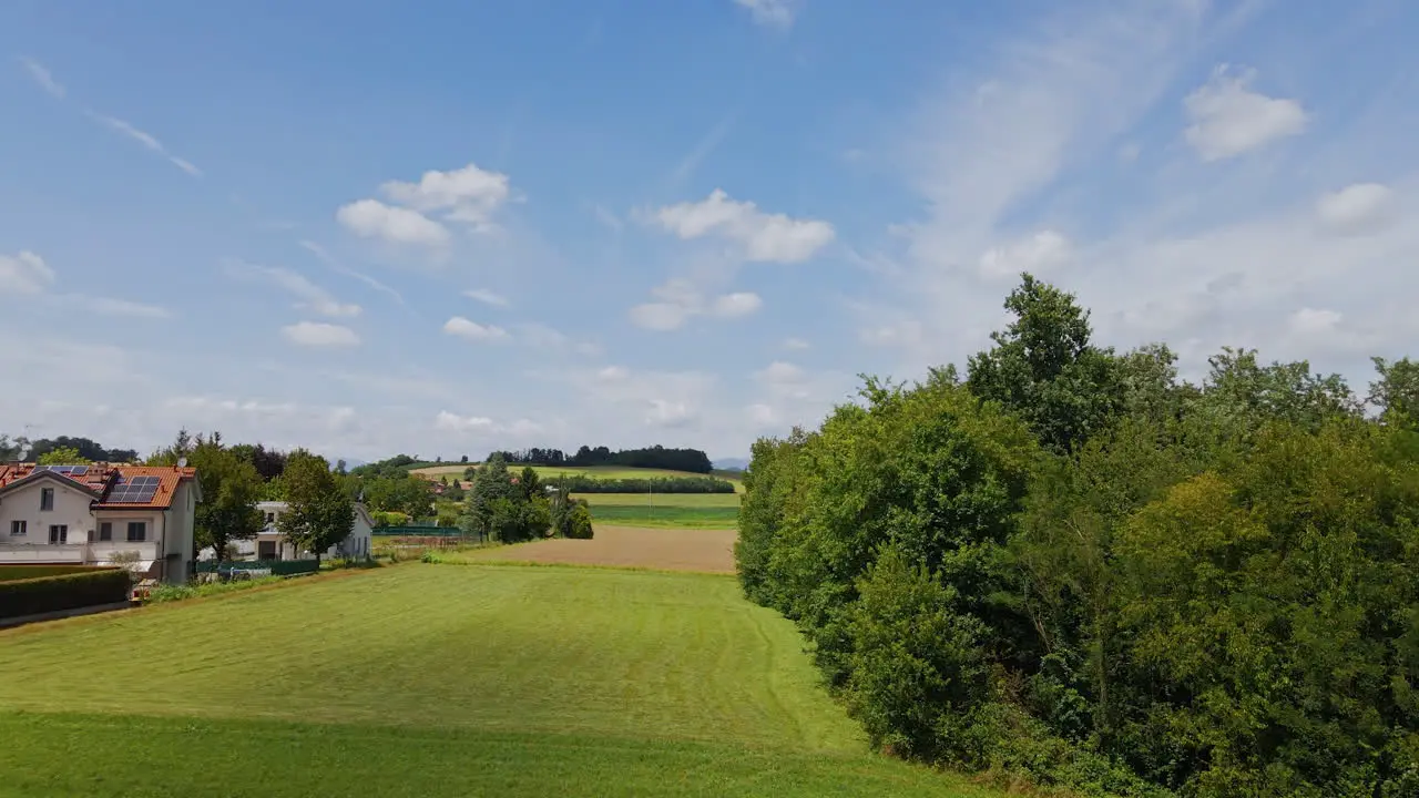 Countryside Landscape With Green Fields Blue Sky And Residential Houses During A Beautiful Sunny Day In Northern Italy aerial drone shot