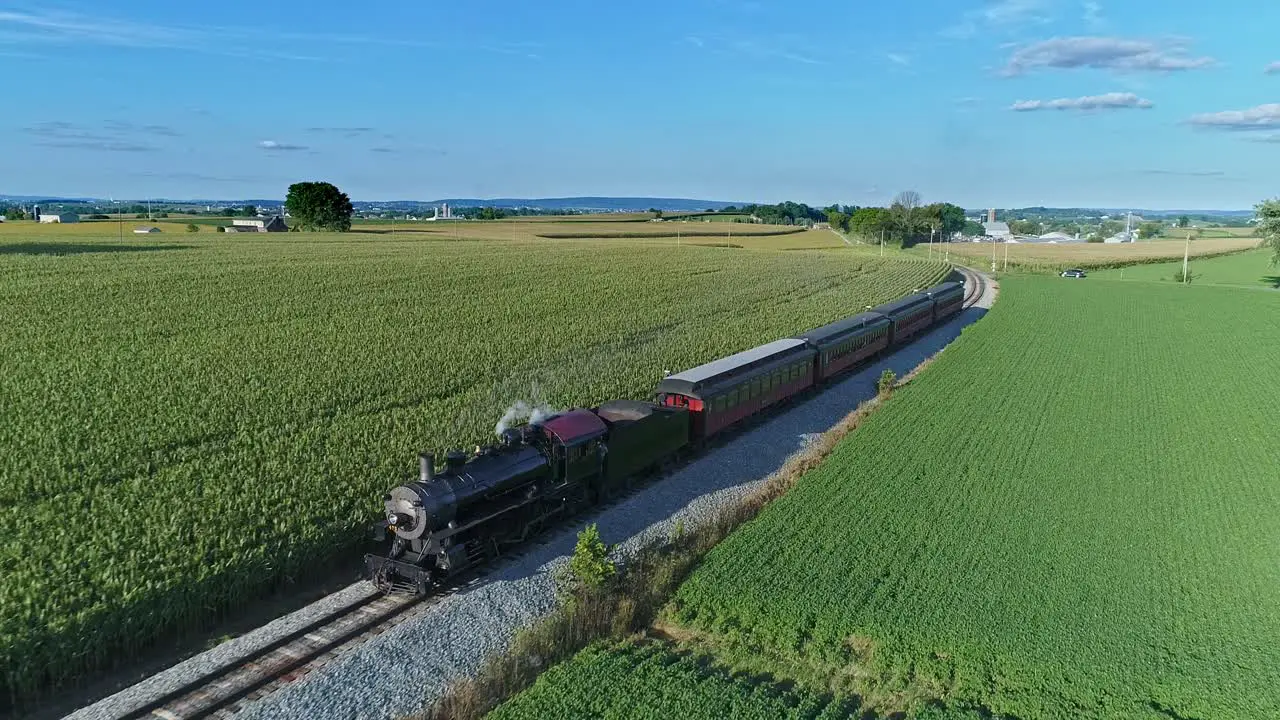 An Aerial View of an Antique Steam Passenger Train Blowing Smoke and Steam Traveling Thru Fertile Corn Fields on a Beautiful Sunny Summer Day