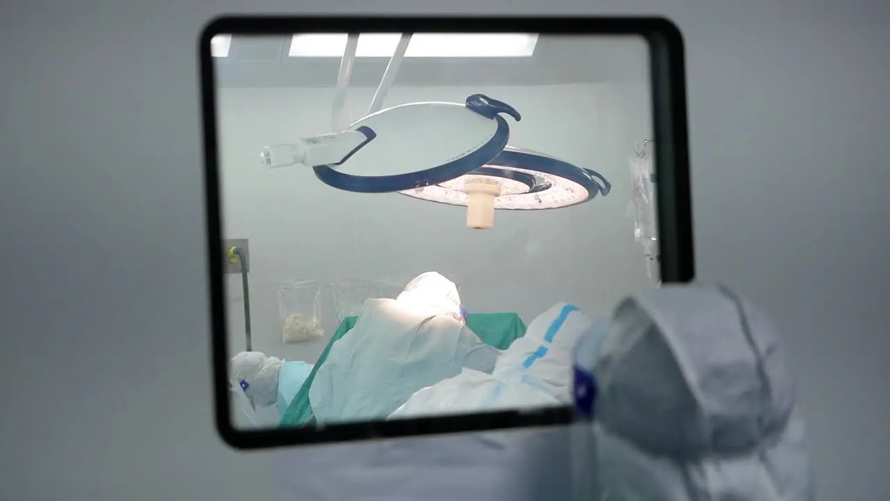 Asian Woman Wear PPE Look Inside Operating Room Window Close Up