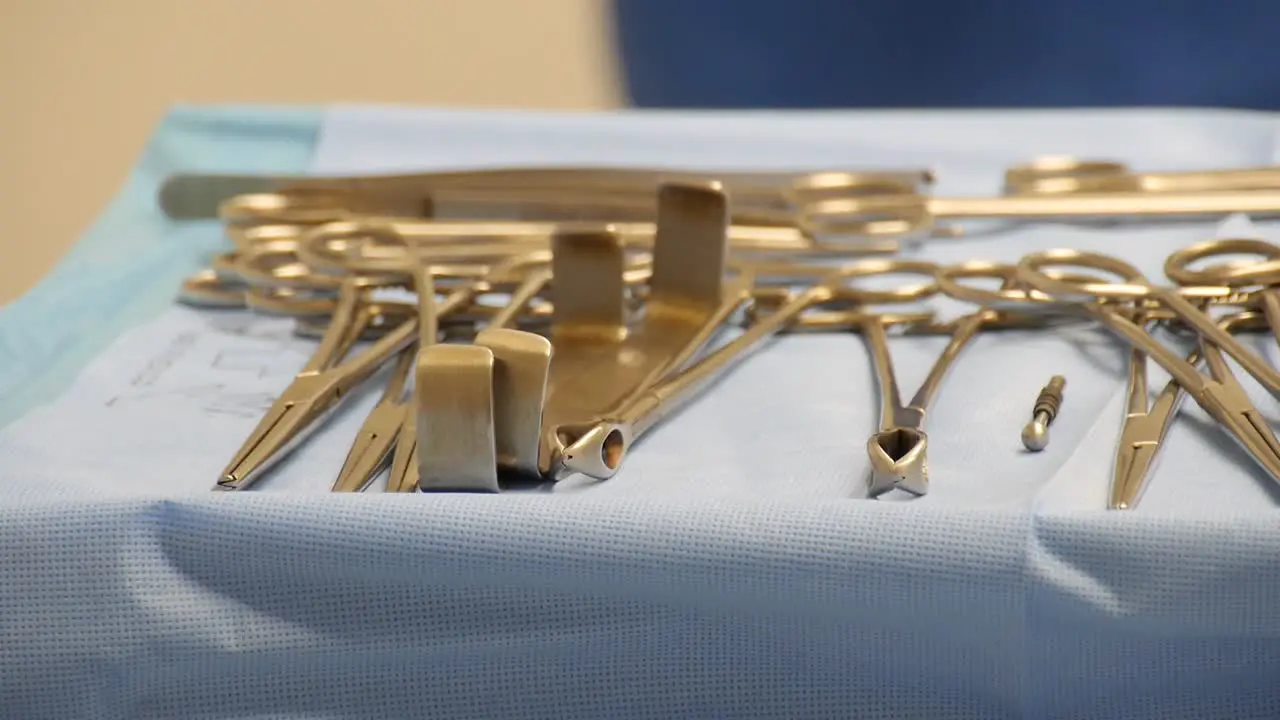 Close-up of a sterile surgical tray full of operating instruments with motion a healthcare worker moving in the background