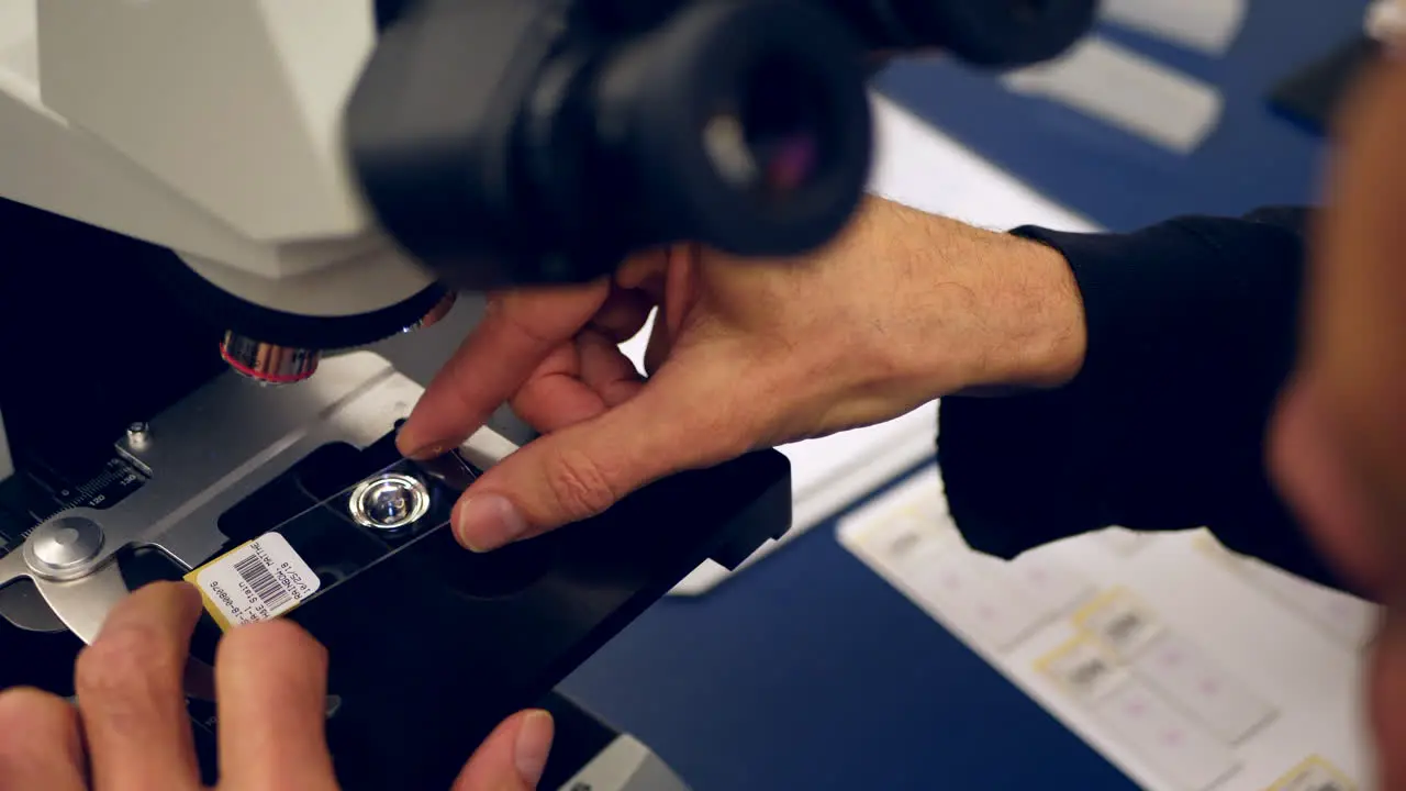 A scientist preparing a slide of his own cancer cells from a medical biopsy on a microscope in a medical research science lab