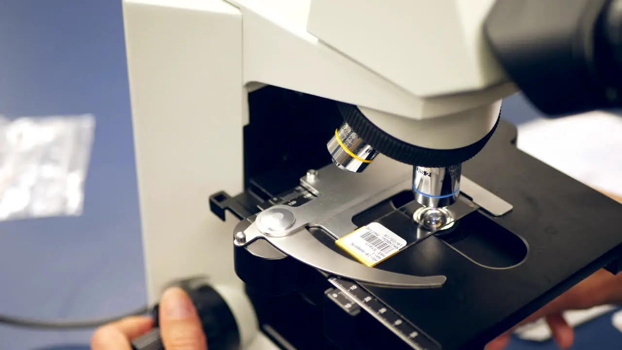 A scientist examining a slide of human cells with a microscope in a medical research science laboratory