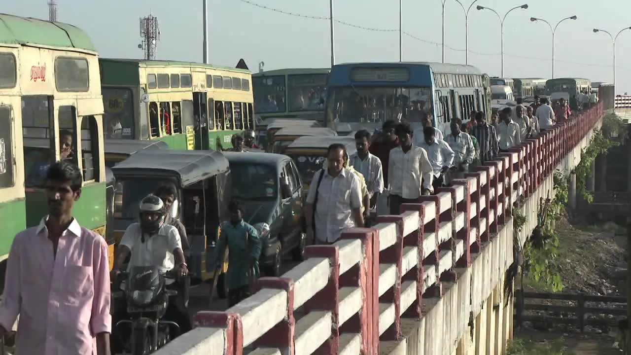 People walk down a sidewalk next to lanes of unmoving cars and buses