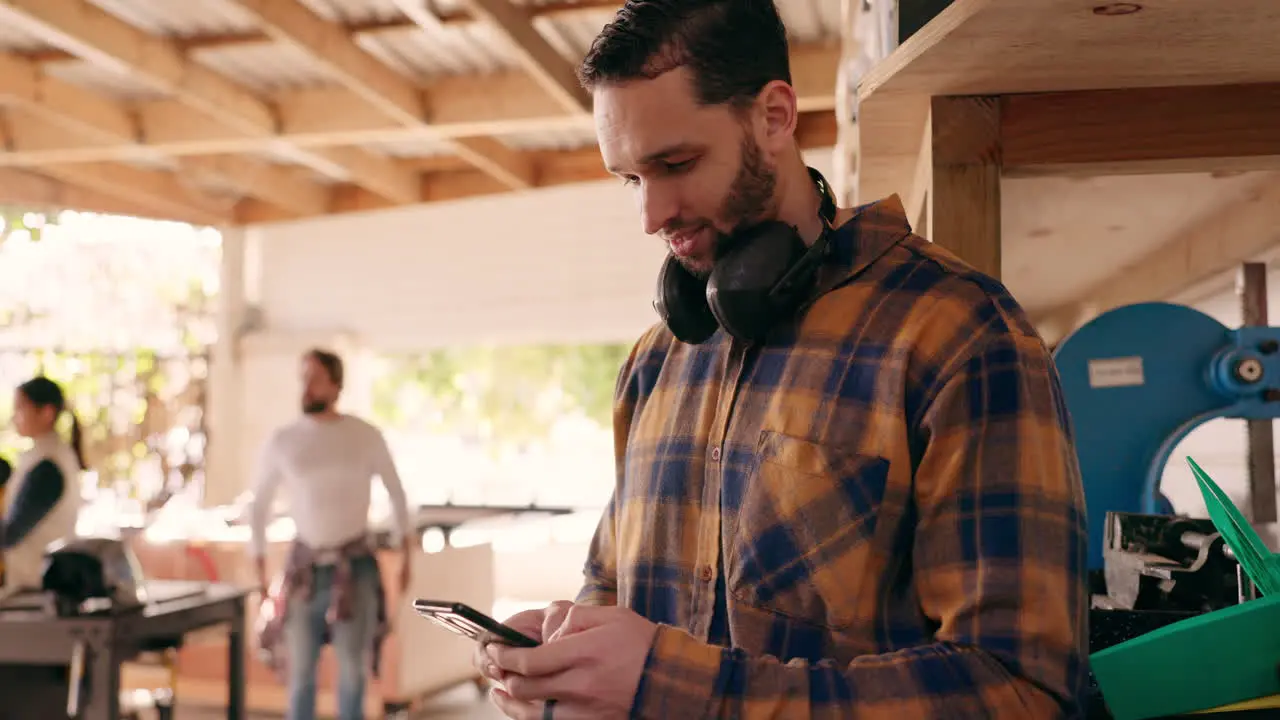 Carpenter man phone and texting in workshop