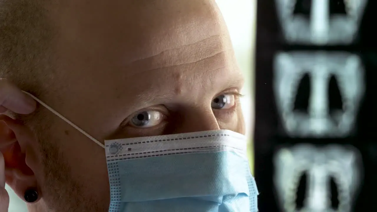 Caucasian doctor with gray eyes putting on Surgical mask and Protective glasses