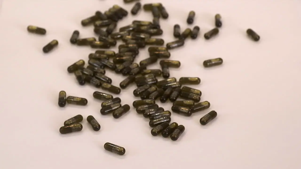 Brown cannabis oil capsule pills are poured from small glass bottle