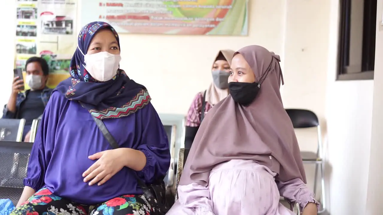 Two attractive pregnant women talking to another patient while waiting for gynecologist check up