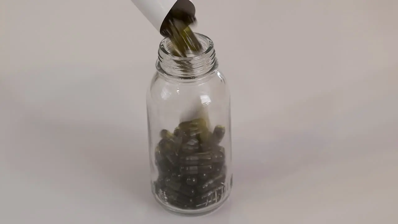 Small glass bottle is filled with golden brown pill capsules