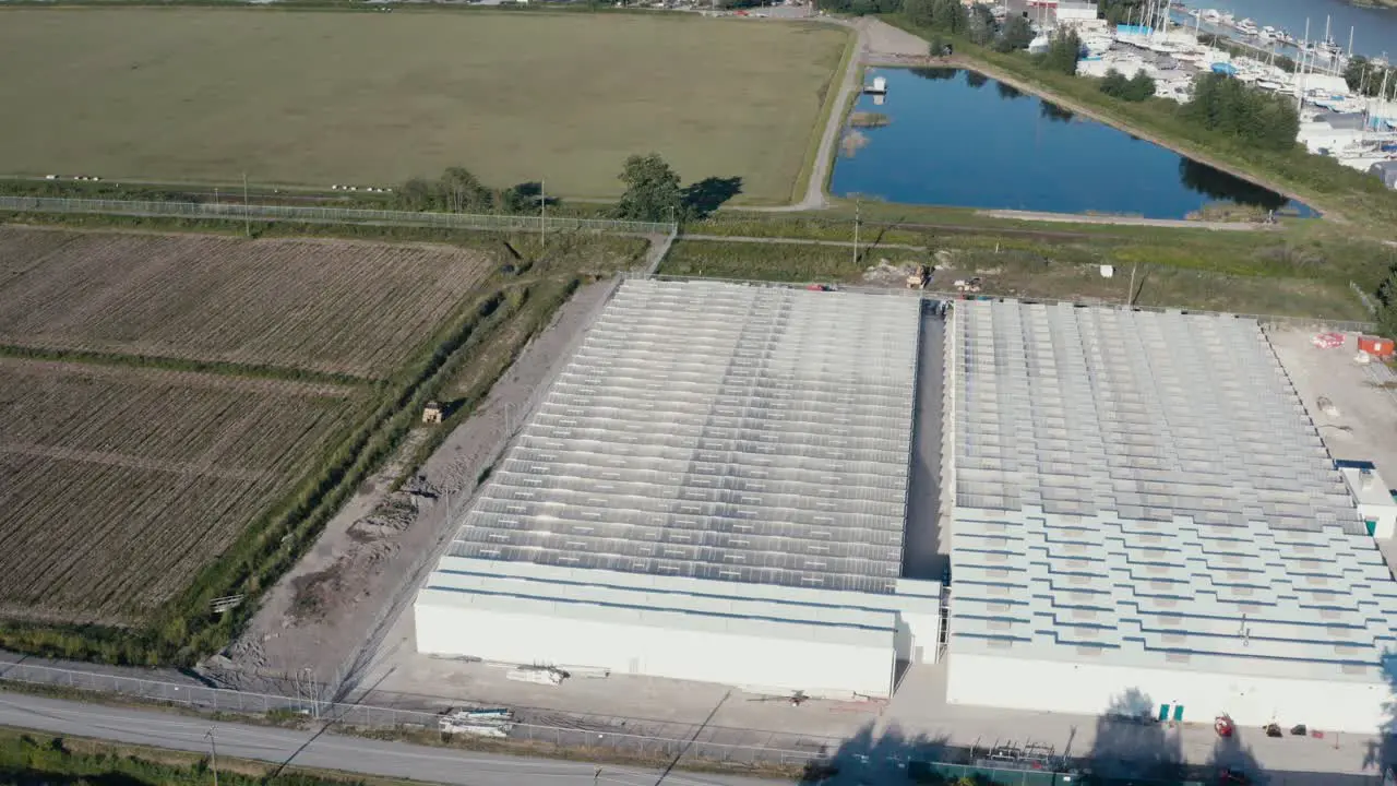 Aerial birds eye view fly over bobwire Givernment regulated secure cannabis farming pricessing facility greenhouse next to winery cranberry farm in Richmond BC Canada connected to Fraser RIver Port