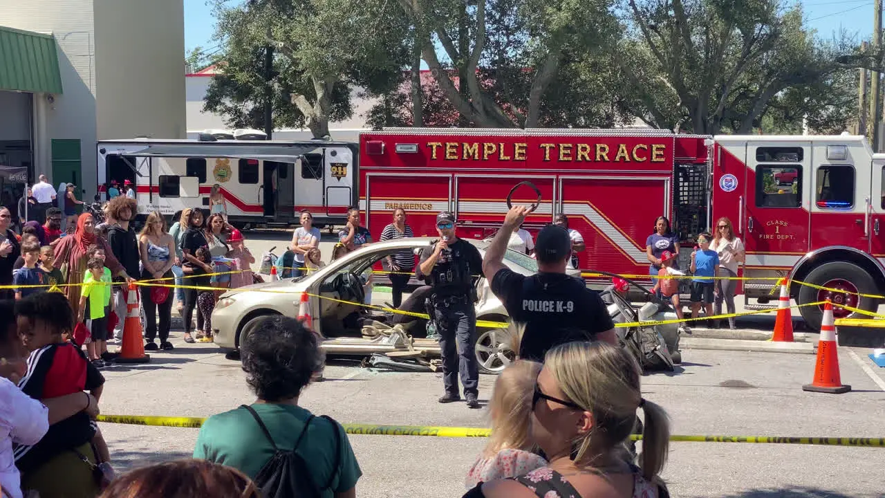 Static handheld shot of a Police Officer talking to a crowd at a demonstration for kids at an Annual Fire Department Open House event organized by Temple Terrace Florida