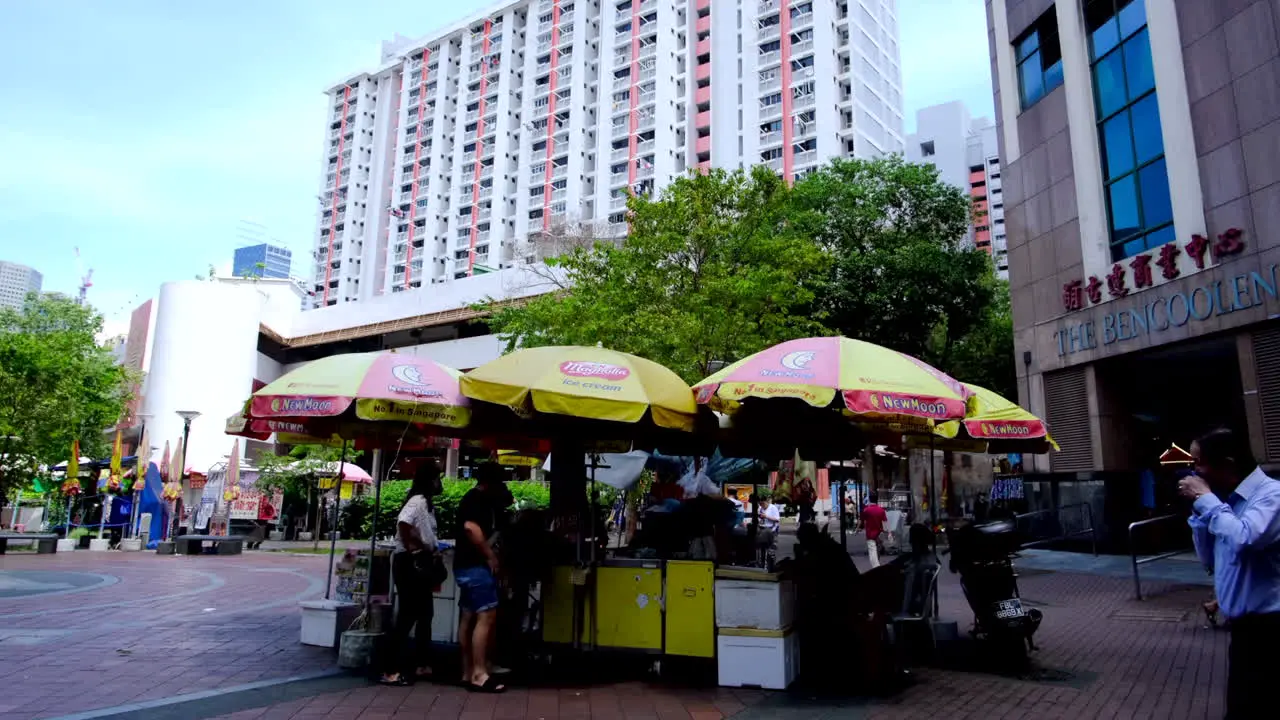 Mini store set up with just umbrellas and a counter top in front of the tall building in Singapore