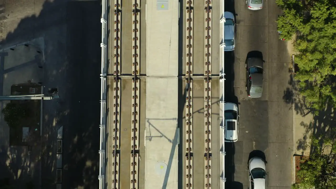 Top Down Aerial View of Elevated Train Tracks Over Urban Street with Cars Empty