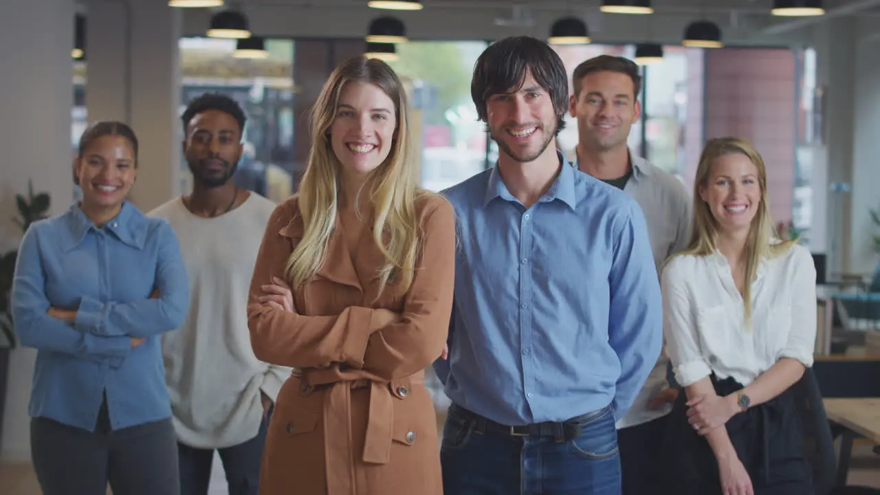 Portrait Of Couple Leading Multi-Cultural Business Team Standing In Modern Open Plan Office