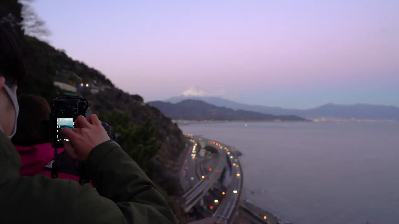 Photographer wearing facemask during Covid Pandemic taking pictures of landscape with Mount Fuji