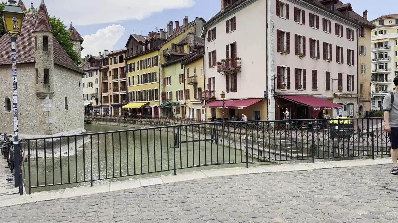 Busy pedestrian bridge in Annecy with tourists stopping to photograph scenery