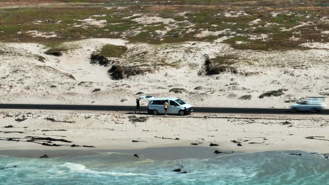 Slide and pan footage of passenger van standing next to road on sea coast Waves washing sand South Africa