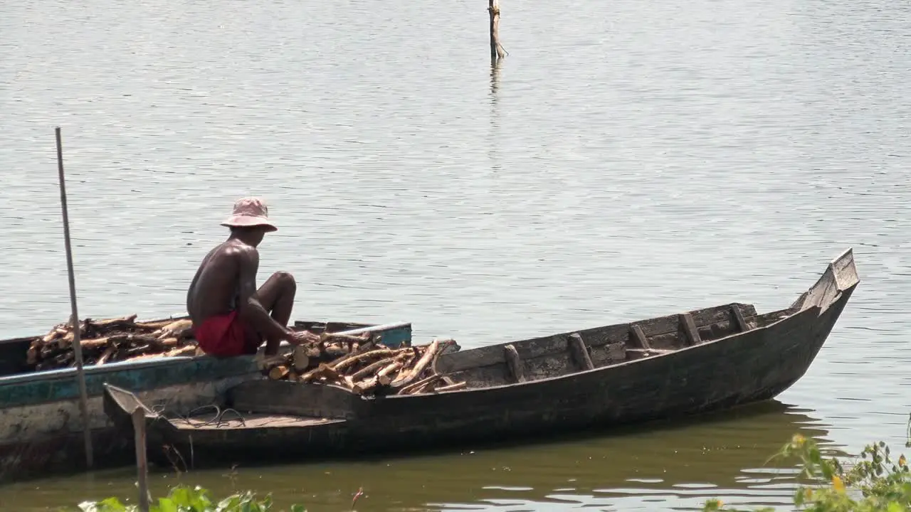 Man Sorting Firewood in Boat