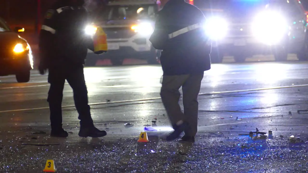 Police officers investigating vehicles collision scene at night