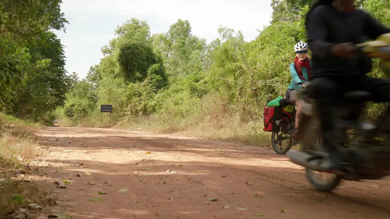 Man on motorbike overtake a woman on bicycle while she waits