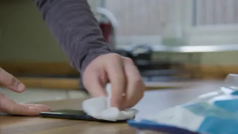 Sliding Close Up of Male Hands Cleaning a Mobile Phone with Anti Bacterial Wipe