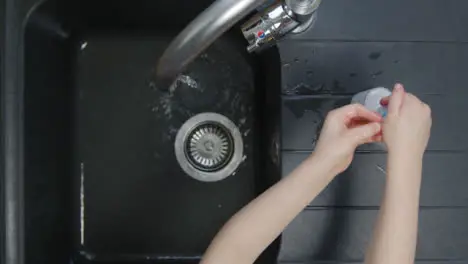 Top Down Shot of Young Childs Hands Washing with Soap Under Kitchen Tap