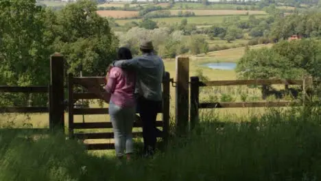 Tracking Shot Approaching Middle Aged Couple Looking Out at Countryside Valley