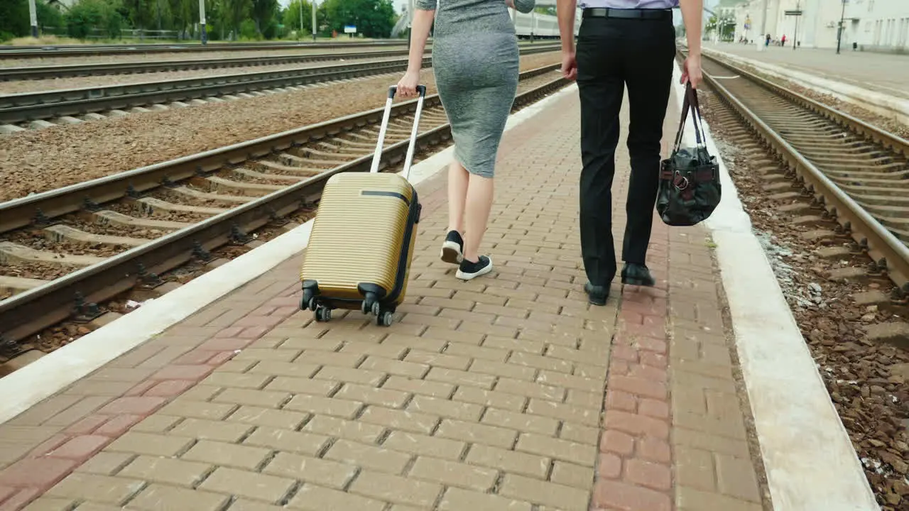 Two Business People Walk Along The Railway With Their Luggage