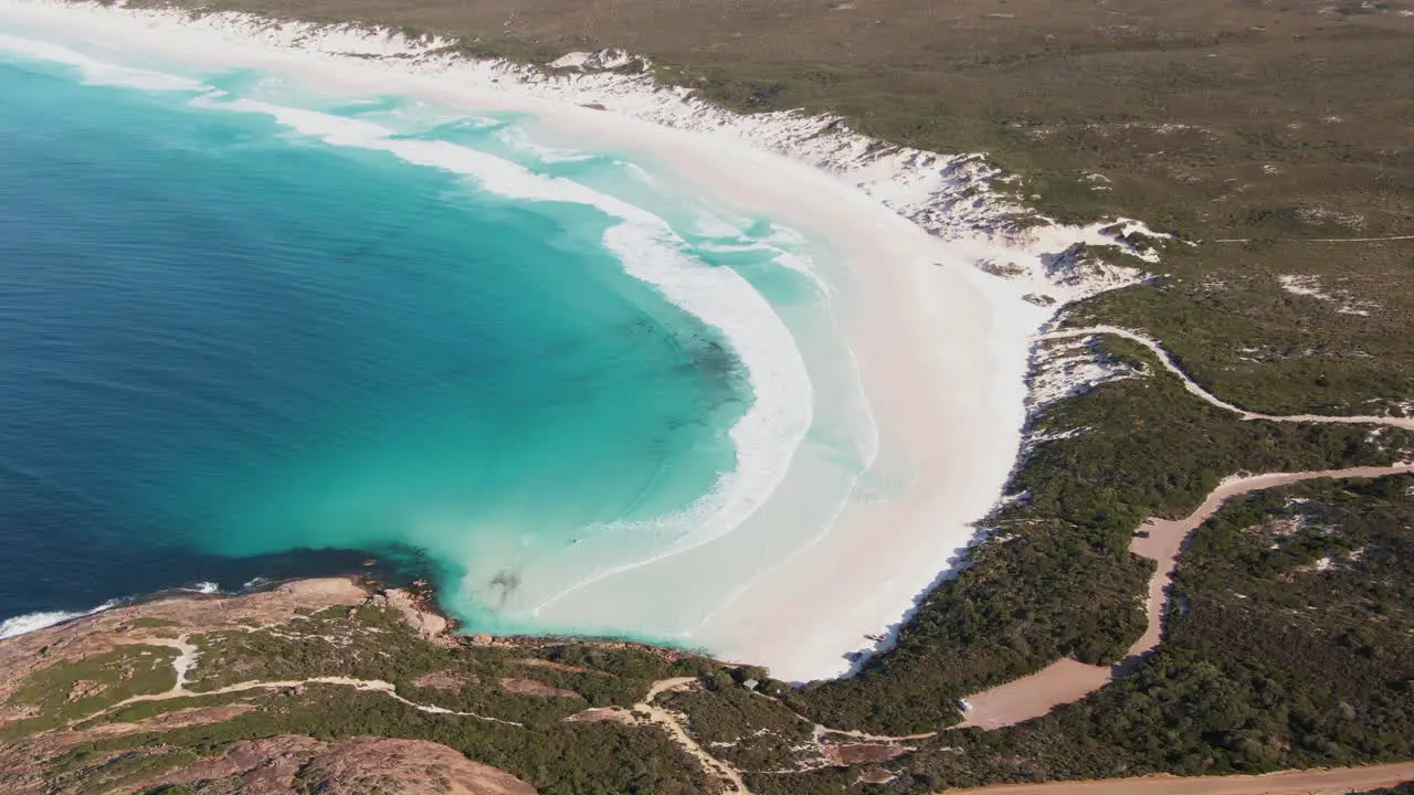 Waves from the turquoise see rolling onto an empty white beach