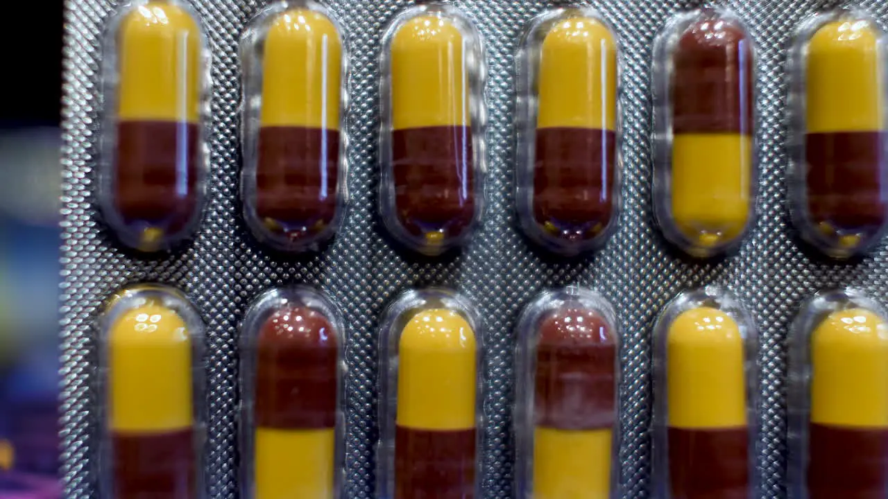 A close-up view of Amoxicillin Capsules as the dark red and yellow components are delicately arranged into their original packaging encapsulates the essence of medical care and treatment