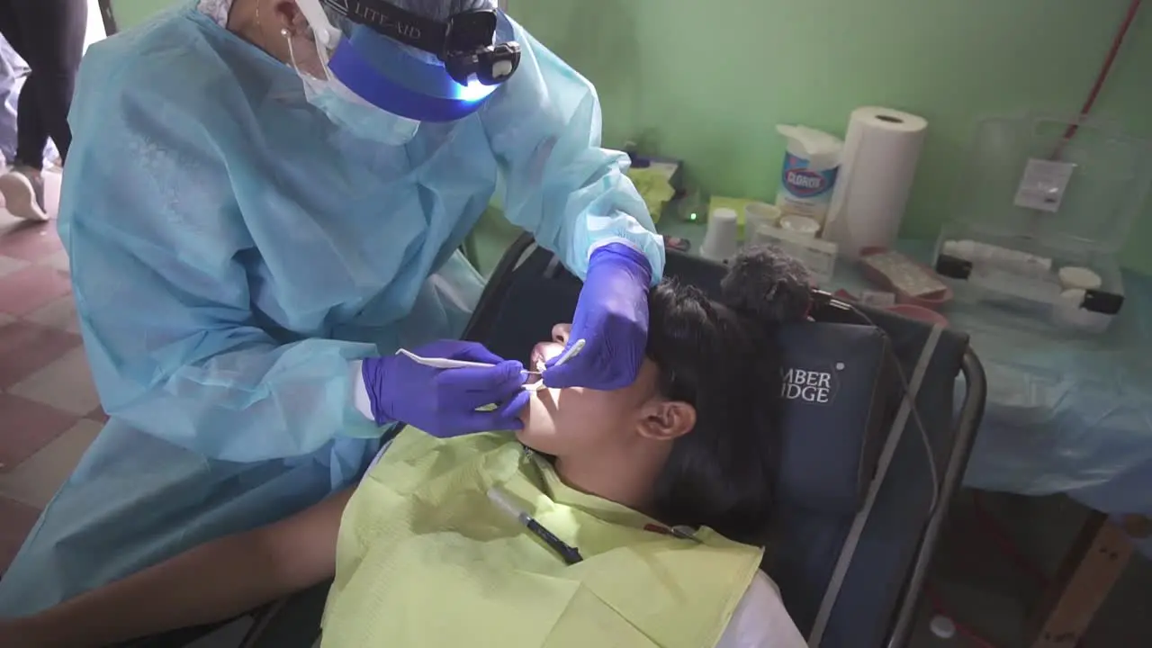 Dentist woman treats a little girl during a medical brigade in an improvised clinic in a school in a poor community