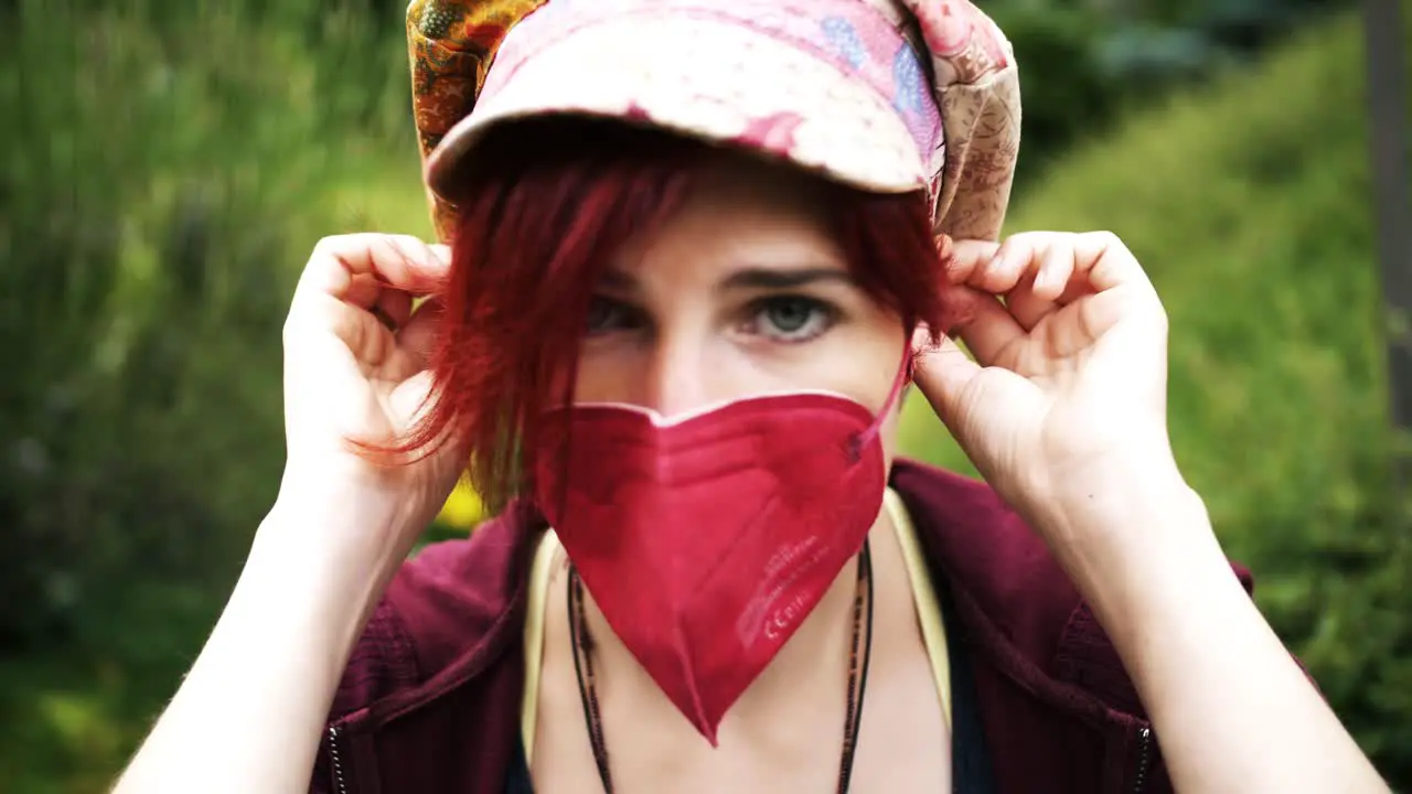 Slow Motion Shot of red haired girl with colorful cap putting on an red anti-corona medical mask