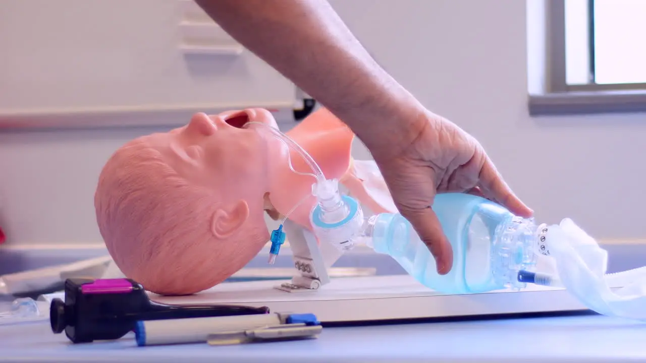 An intubated medical paediatric manikin being ventilated with a bag valve self inflating bag