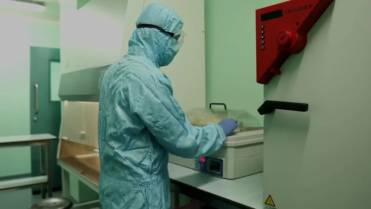 Laboratory Specialists In Full PPE Closing Lid With Samples In Box