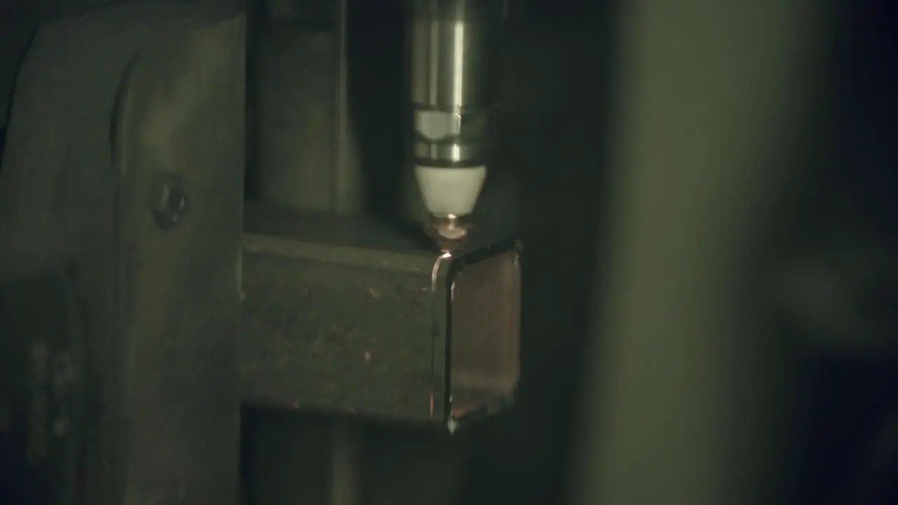 Close up slow motion footage of a laser cutter machine cutting through a steel box pipe