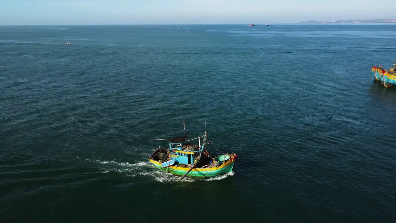 Aerial tracking shot of fisherman boat returning home after fishing day