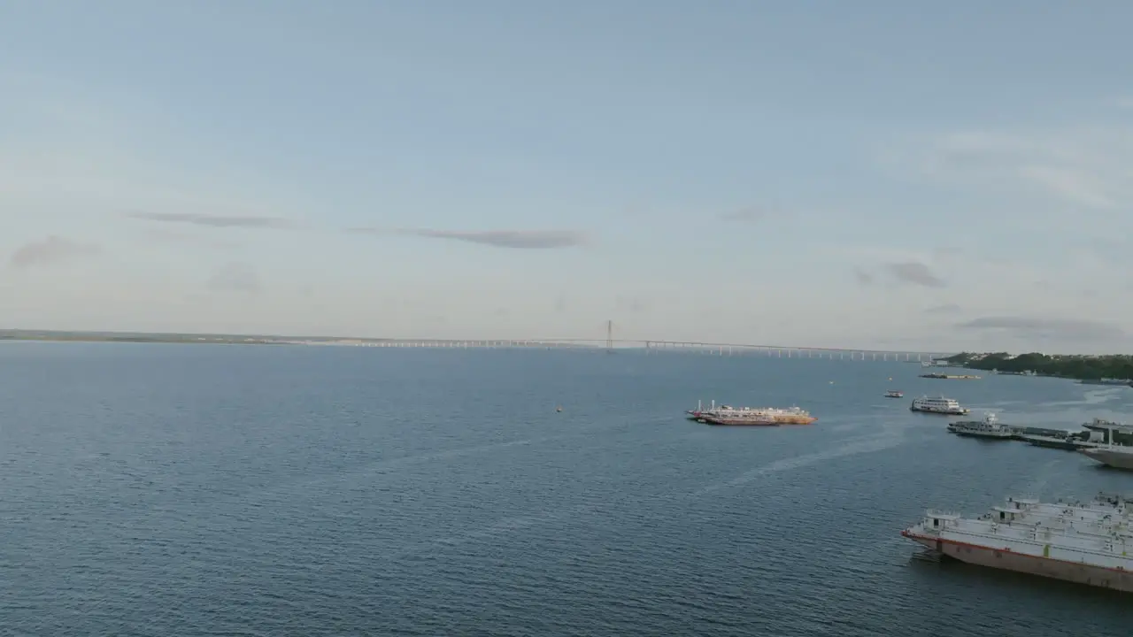 Aerial video of ships docked on the Amazon River with the Rio Negro Bridge in the background