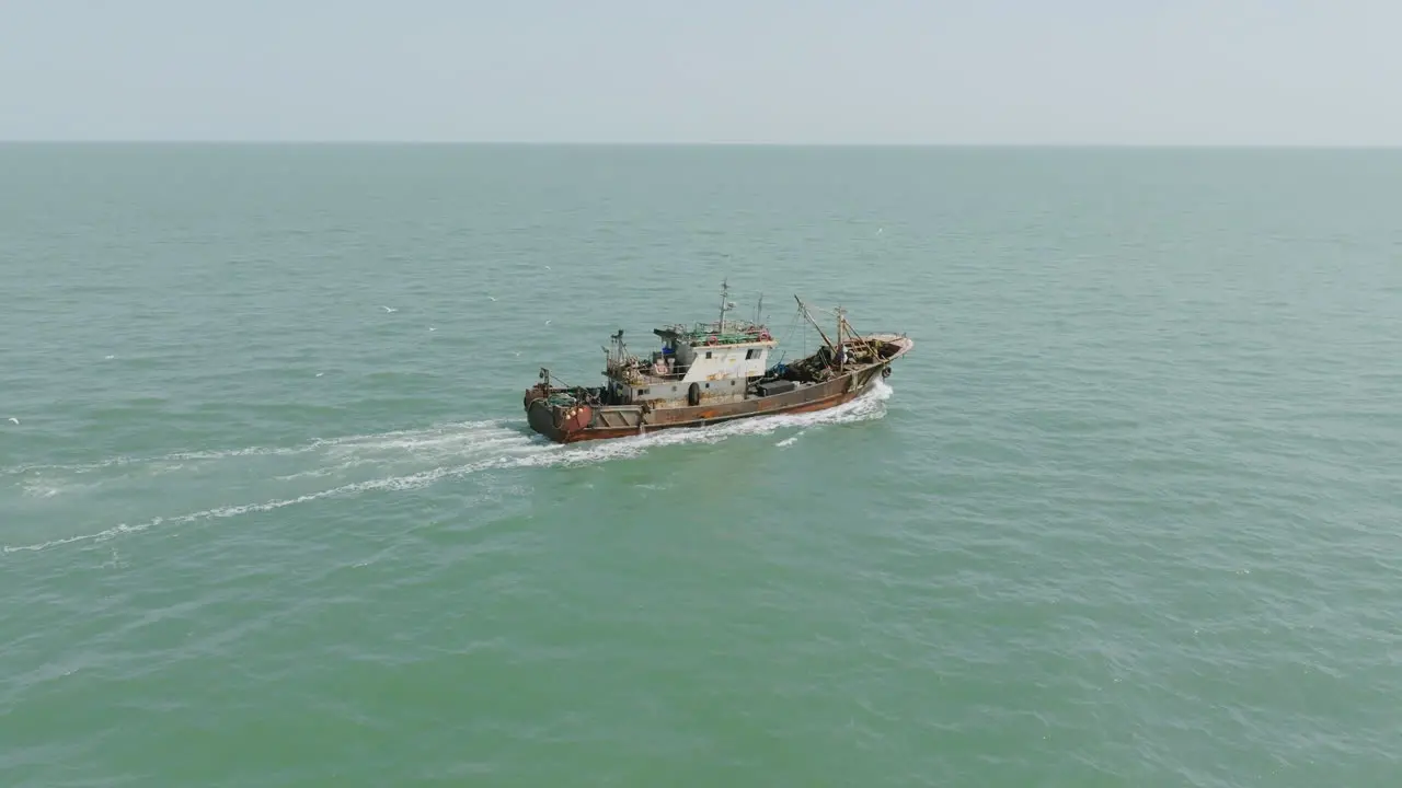 Fast aerial footage following a fishing trawler that is traveling off the coast of The Gambia