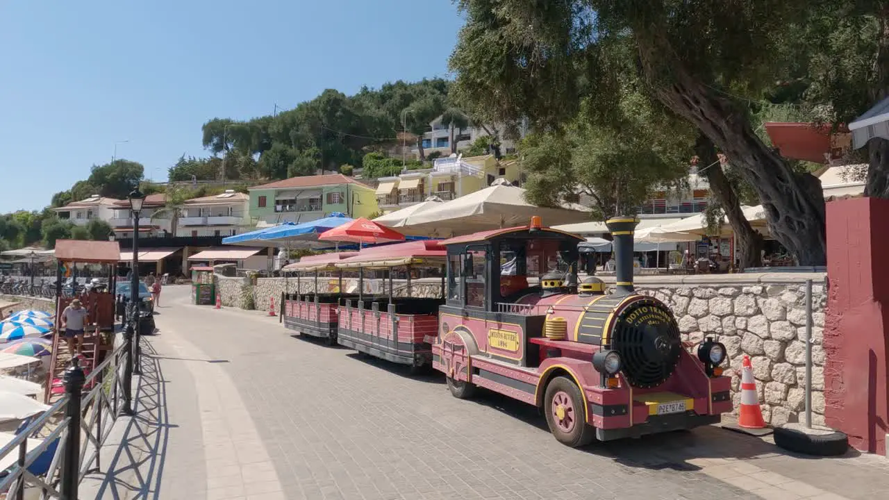 Couple walking along promenade passing by a touristic street train Parga Greece