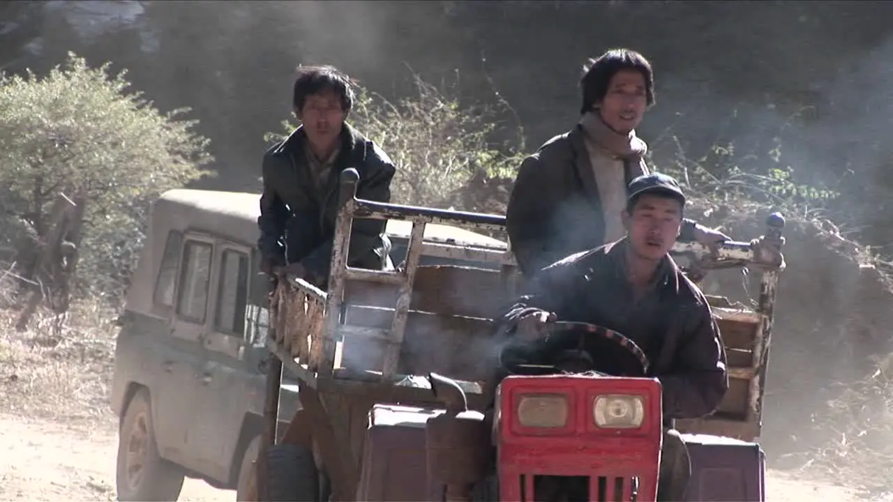 Men drive a primitive tractor across a rural landscape in China