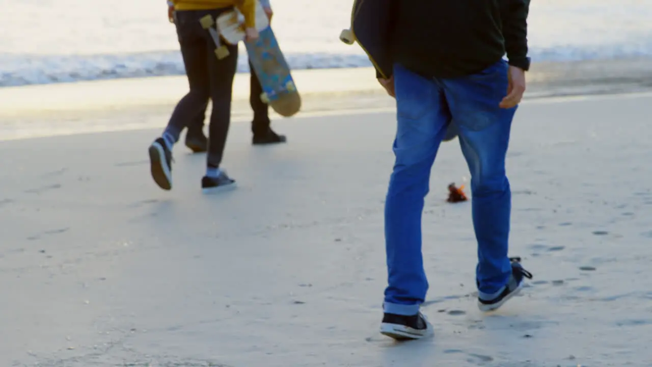 Rear view of young caucasian friends walking together at the beach during sunset 4k