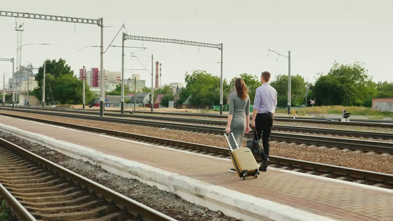 Two Businessmen With Luggage Go Along The Railroad