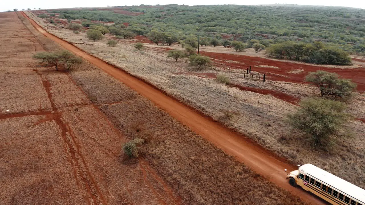 Aerial over a school bus traveling on a generic rural dirt road on Molokai Hawaii from Maunaloa to Hale o Lono