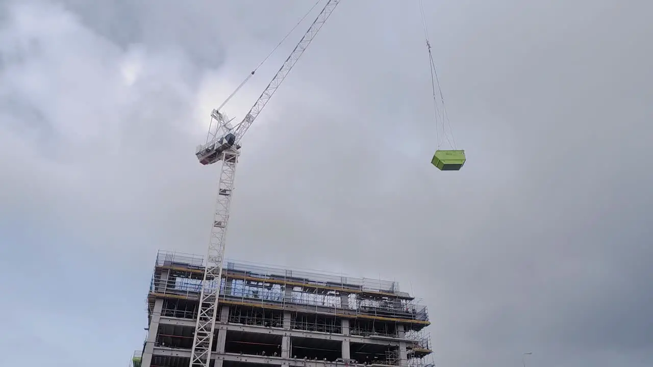 Construction crane lifts a 6m waste bin to top level of construction site