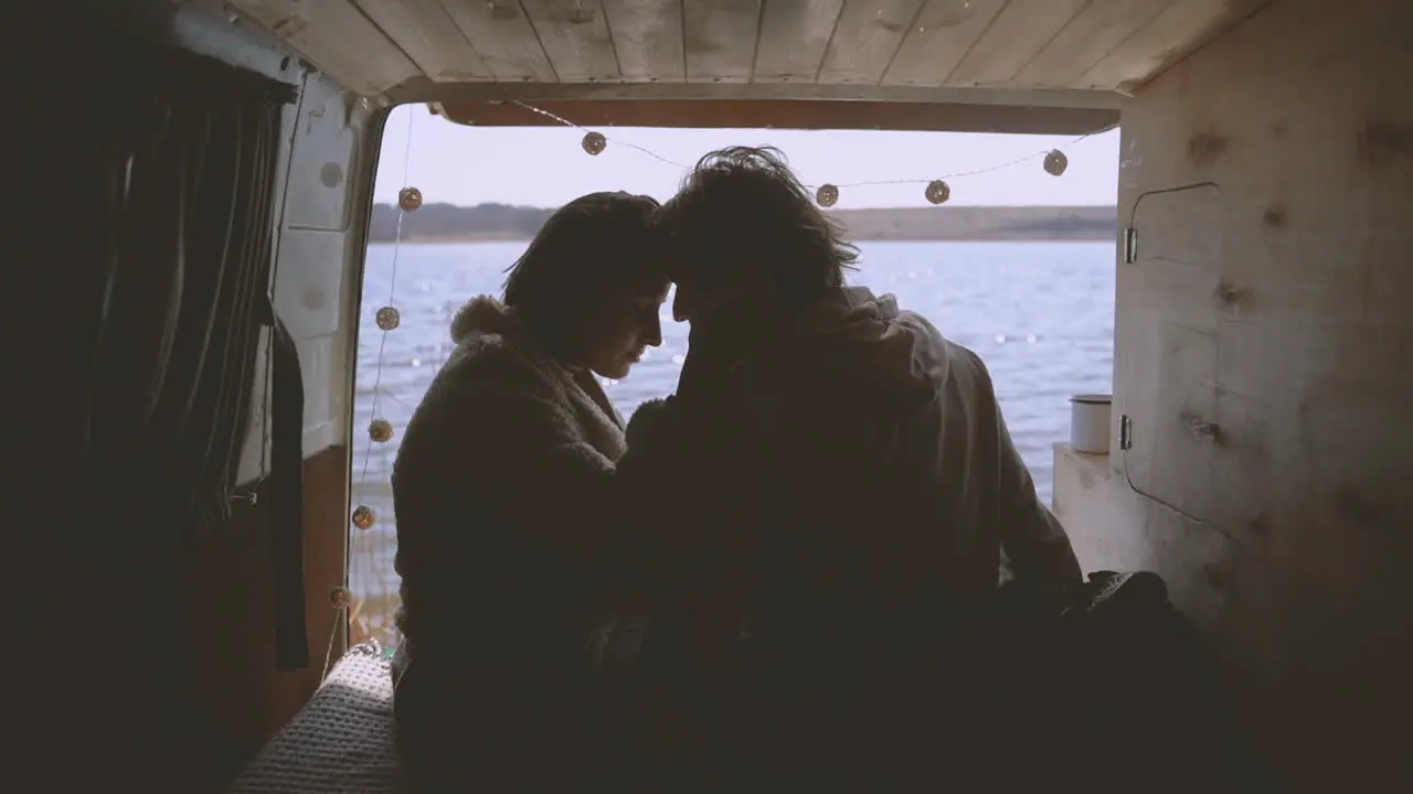 A Young Couple In Love Put Their Heads Together In The Back Of A Caravan By A Lake 1