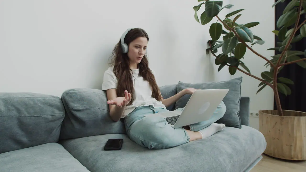 Cute Young Female Makes A Video Call With Her Laptop From The Sofa At Home